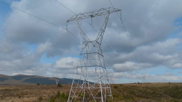 High-voltage transmission towers carry electricity across the landscape in Tongariro, New Zealand. These power lines are essential for distributing energy.