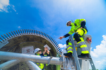 Technical wind farm staff discussing installation plans and pointing towards turbine structures at a large-scale renewable power generation site. © ultramansk