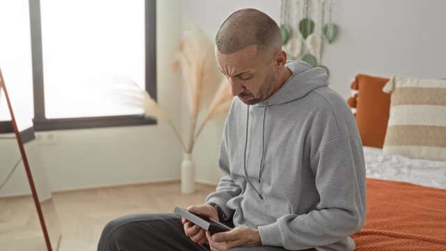 Man holding a photo frame to his chest on a bed inside a building, hand gripping frame tightly; grief memory longing.