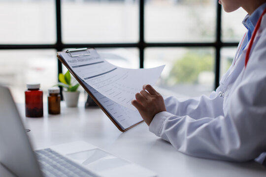 Doctor reviewing health assessment form on clipboard, providing medical care and diagnosis, ensuring patient data privacy and a thorough healthcare process in a clinic or hospital setting