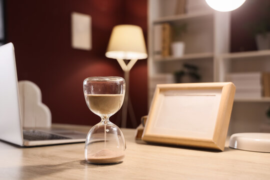 Hourglass on desk in office at night, closeup