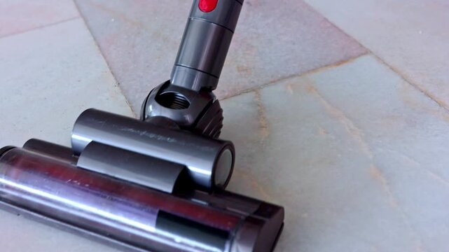 Cordless vacuum cleaner sucking dirt from a marble floor