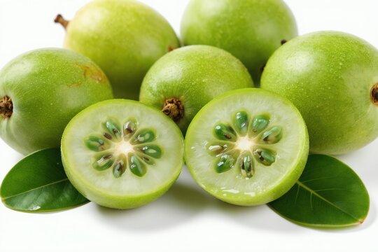 Green amla fruits whole and halved with visible seeds on white background. Fresh organic Indian gooseberries with green leaves. Healthy raw natural food ingredient.