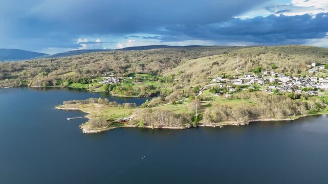 Aerial view of Encoro de Prada reservoir with green hills and small villages under a cloudy sky in A Veiga, Ourense, Spain.