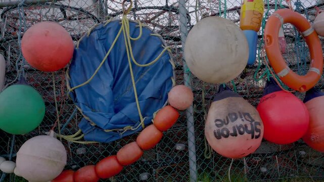 A variety of fishing floats hanging on wire fence