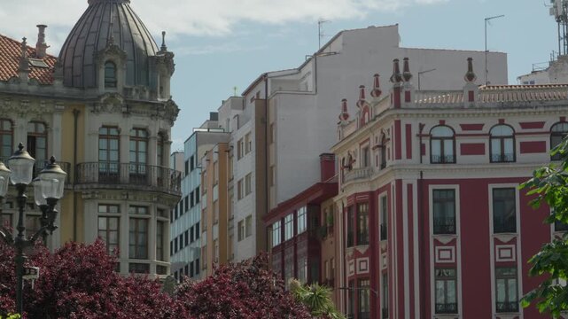 Shot panning across ornate colorful facades and domed building at Plaza San Miguel, Gijon.