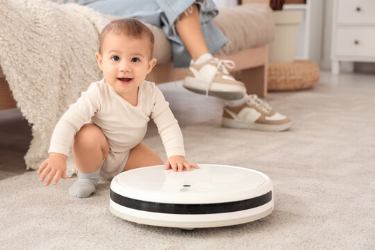 Cute little baby with robot vacuum cleaner and mother sitting on sofa at home, closeup