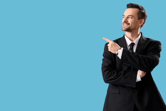 Portrait of male real estate agent pointing at something on blue background
