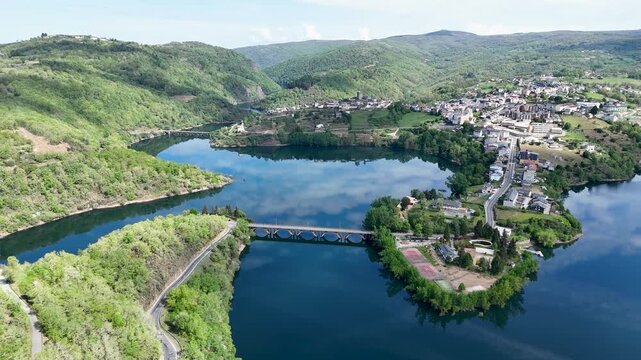 Aerial view of the historic town of Viana do Bolo surrounded by a calm reservoir and lush green hills in Viana do Bolo, Province of Ourense, Spain.