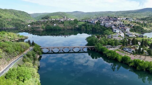 Aerial view of the historic town of Viana do Bolo situated on a hill surrounded by the Bao Reservoir with a bridge and lush green mountains in Viana do Bolo, Province of Ourense, Spain.