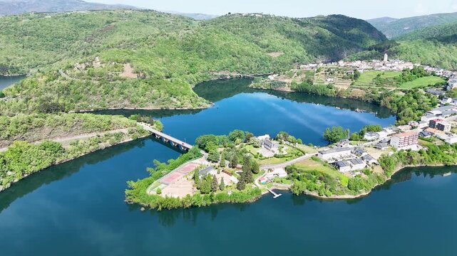Aerial view of Viana do Bolo town surrounded by the blue waters of Bao Reservoir and lush green hills in Viana do Bolo, Province of Ourense, Spain.