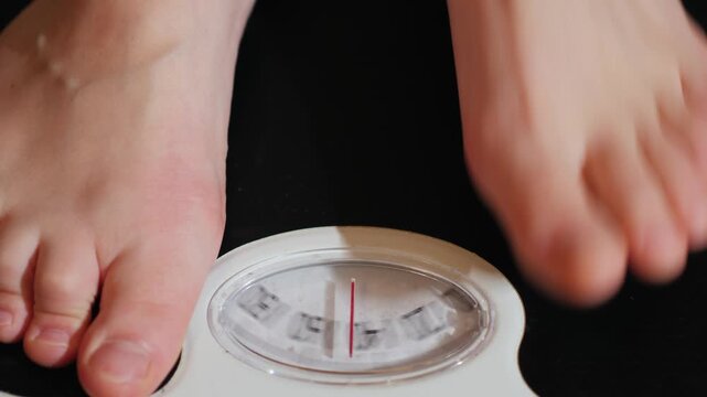 A close up shot of a person stepping onto an old analog scale, measuring their weight in a motion clip.