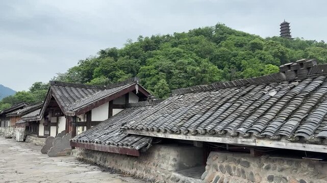 A static 4K view of ancient grey tiled roofs with a lush green mountain and traditional pagoda in Dujiangyan China.