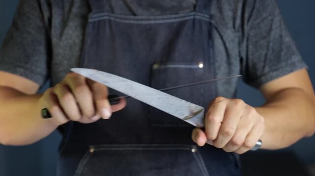 Chef Sharpening Kitchen Knife with Honing Steel, Professional Cook in Apron, Close Up 4K