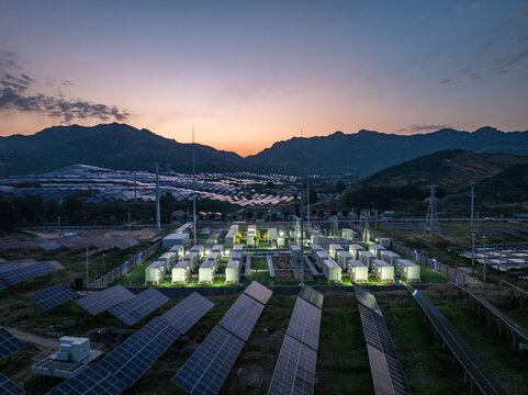 Photovoltaic power station with energy storage facilities at dusk in mountainous terrain