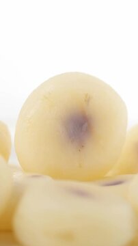 Slowly rotating boiled and peeled water chestnuts arranged on a white background, Close-up view 