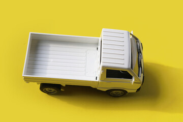 White toy pickup truck on a bright yellow background. © Bowonpat