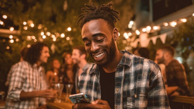 A man in a candid moment, looking at his phone and laughing with friends during a social event.