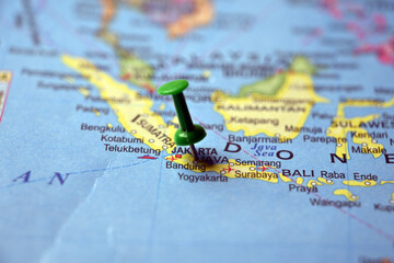 Naklejka premium Green Push Pin Pointing Java Island on Paper World Map Macro Close Up with Blurred Background