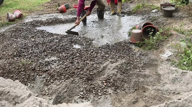 Construction footage of workers preparing wet concrete mixture at active residential building site.