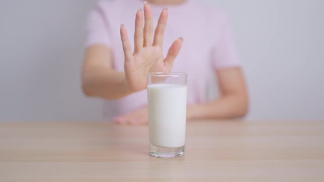 Lactose intolerance and Milk allergy. woman hand stop and refuse Milk, having abdominal cramps and pain when drink Cow Milk. Symptom stomach ache, Dairy intolerant, Nausea, Bloating, Gas and Diarrhea