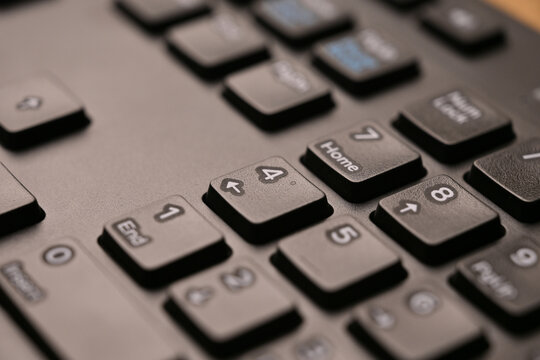 Black Computer Keyboard Macro Shot Highlighting Num Lock Area 4 Key on Numeric Keypad with Soft Blurred Background Angled Top View