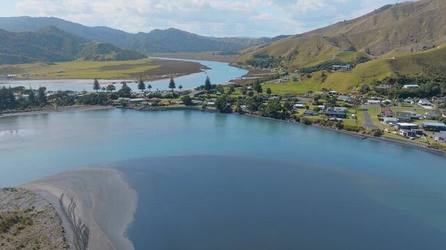 Aerial view of tranquil Marokopa, New Zealand, where the river meets the sea. The scene captures the beauty of the landscape and the peacefulness of the coastal village.