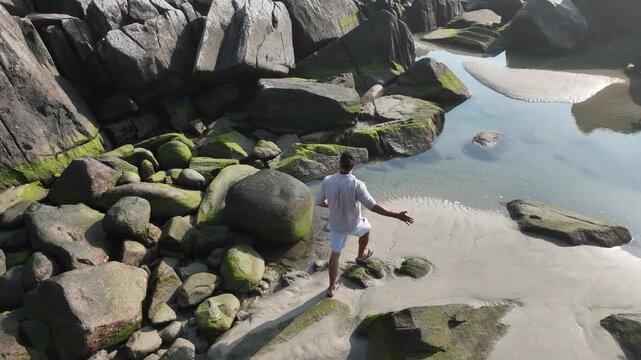 Ponta das Campanhas, Armacao in Florianopolis. A man walks across the island among the rocks. Aerial view 