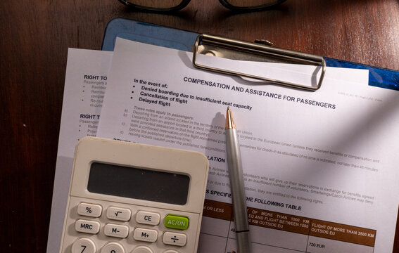 High angle view of Smartwings compensation and assistance for passengers form on a clipboard with a silver pen and a calculator on a wooden desk