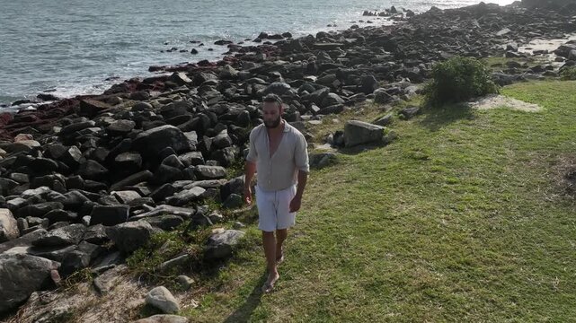 Ponta das Campanhas, Armacao in Florianopolis. A man walks across the island among the rocks. Aerial view 