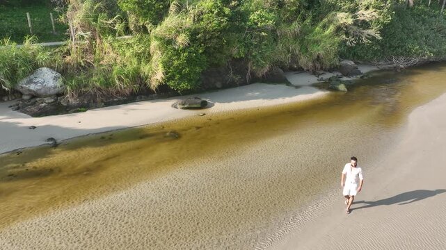 Ponta das Campanhas, Armacao in Florianopolis. A man walks across the island among the rocks. Aerial view 