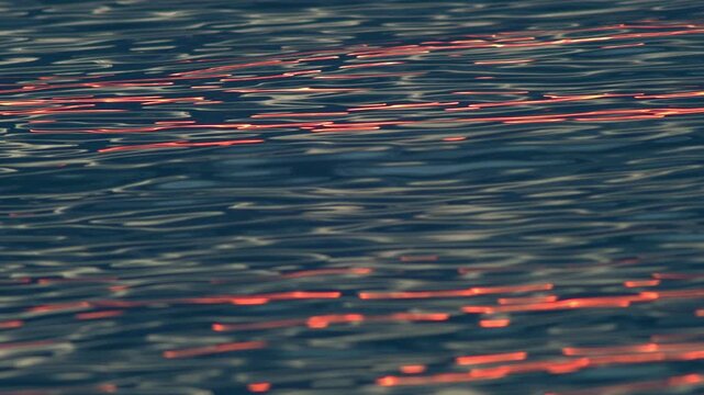Dark Ocean Surface With Crimson Sunset Reflections and Rolling Wave Patterns