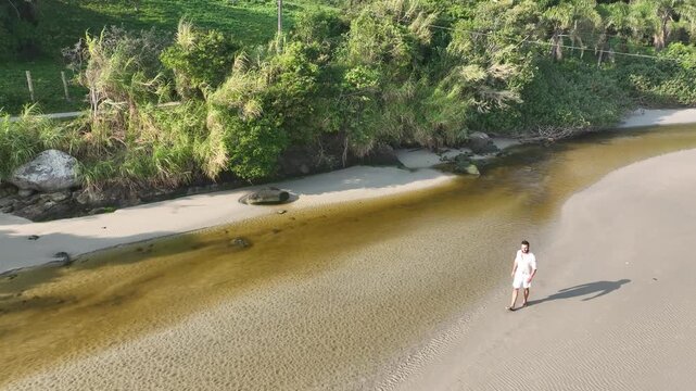 Ponta das Campanhas, Armacao in Florianopolis. A man walks across the island among the rocks. Aerial view 