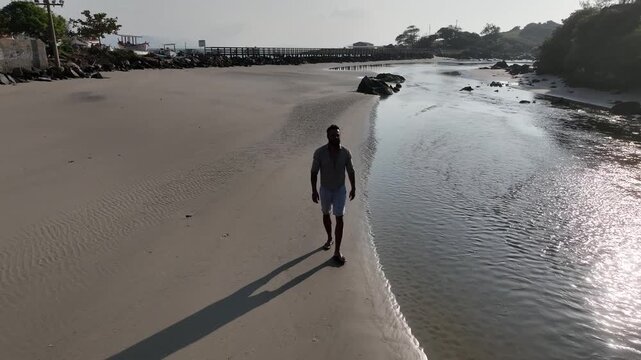 Ponta das Campanhas, Armacao in Florianopolis. A man walks across the island among the rocks. Aerial view 