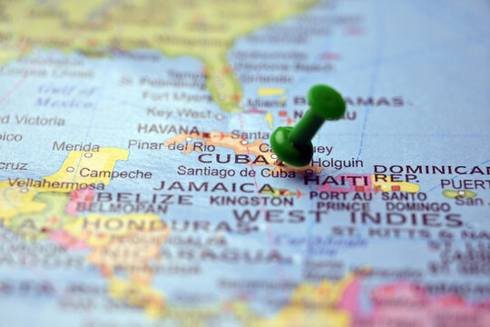 Green Push Pin Highlighting Cuba on Vintage Paper World Map Macro Close Up