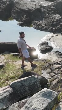 Ponta das Campanhas, Armacao in Florianopolis. A man walks across the island among the rocks. Aerial view.