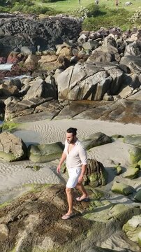 Ponta das Campanhas, Armacao in Florianopolis. A man walks across the island among the rocks. Aerial view.