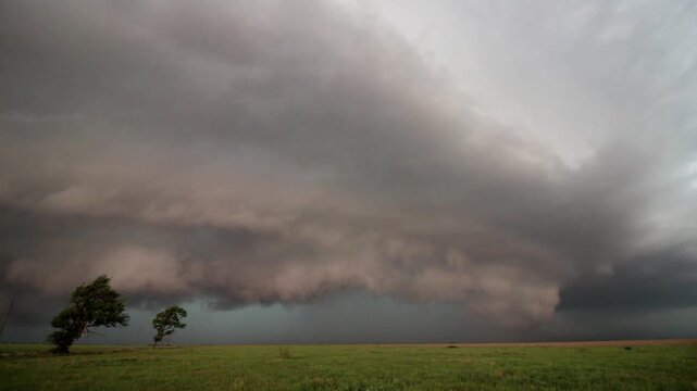 A dark and scary storm advances over a rural area in the great plains in this time lapse footage.