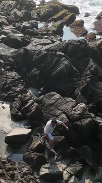 Ponta das Campanhas, Armacao in Florianopolis. A man walks across the island among the rocks. Aerial view.