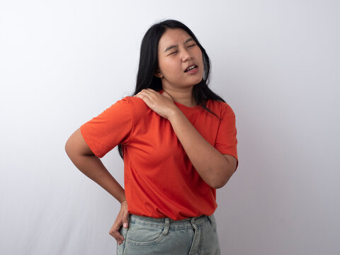 Tired Asian woman suffering from shoulder muscle pain caused by work fatigue and overworking.