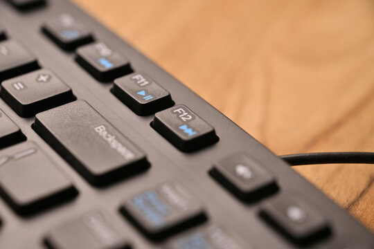 Side Angled Top View Macro Close-Up Black Computer Keyboard Highlighting F12 Function Key on Blurred Tech Background