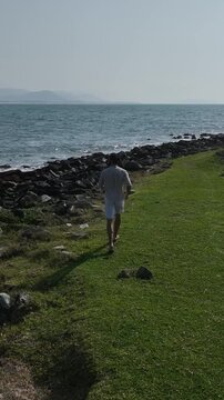 Ponta das Campanhas, Armacao in Florianopolis. A man walks across the island among the rocks. Aerial view.