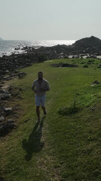 Ponta das Campanhas, Armacao in Florianopolis. A man walks across the island among the rocks. Aerial view.