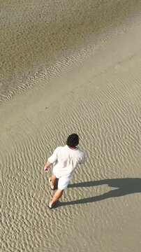 Ponta das Campanhas, Armacao in Florianopolis. A man walks across the island among the rocks. Aerial view.