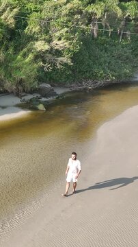 Ponta das Campanhas, Armacao in Florianopolis. A man walks across the island among the rocks. Aerial view.