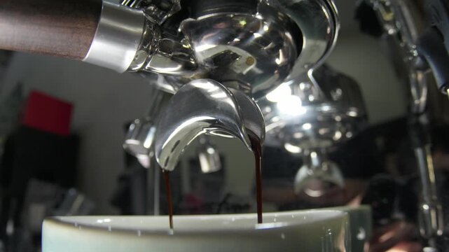 How angle close up of an espresso machine portafilter extracting fresh, dark coffee into a cup. Perfect for cafe branding, hospitality, and morning lifestyle content
