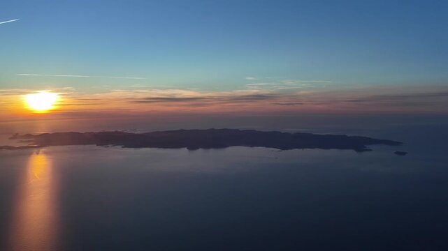 Cockpit view of Ibiza island, in a spinning view with the sun sertting on a golden horizon at the golden minute. Scene taken from an airplane flying at 3000m high.