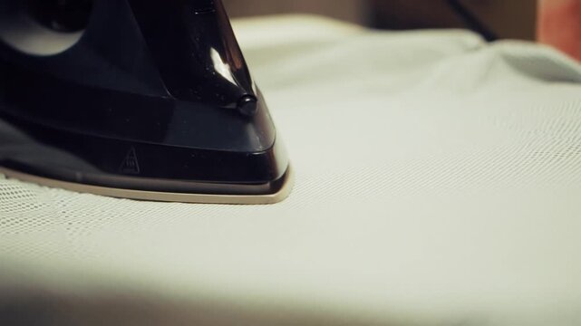 Electric Iron Fabric On Ironing Board. Modern Domestic Appliance Household Chores. Textile Wrinkle Removal 