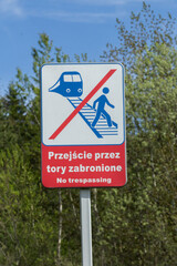  Znak zakazu przejścia przez tory kolejowe z napisem „przejście przez tory zabronione”, ostrzeżenie i bezpieczeństwo na przejeździe. © Henryk Guziak