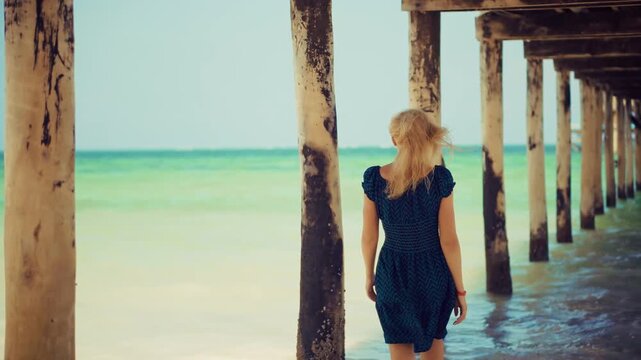 Traveler under Wooden Pier on Tropical Beach. Tourism and Summer Vacation on Exotic Island